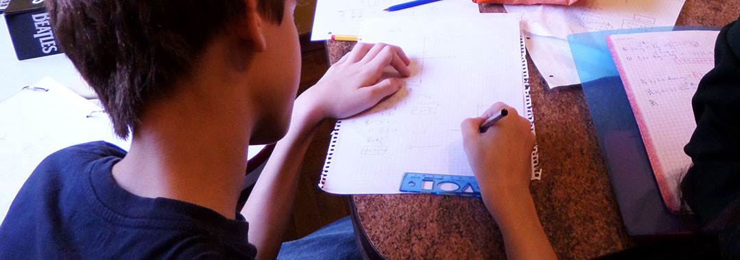 Alumnos estudiando con papeles desparramados.